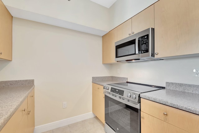 kitchen featuring appliances with stainless steel finishes, light tile patterned floors, baseboards, and light brown cabinetry