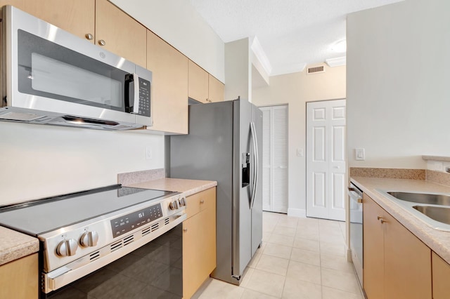 kitchen featuring a sink, visible vents, light countertops, appliances with stainless steel finishes, and crown molding