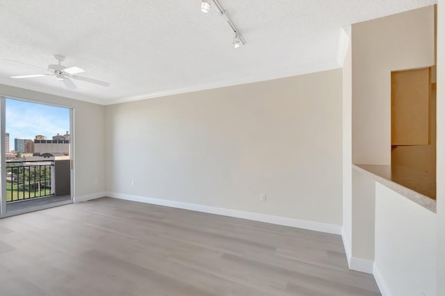 empty room with a textured ceiling, baseboards, and wood finished floors