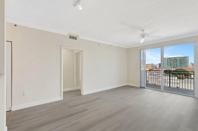 unfurnished room featuring light wood finished floors, crown molding, baseboards, and a textured ceiling