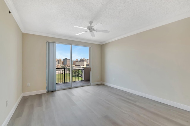 empty room featuring baseboards, ornamental molding, wood finished floors, and a city view