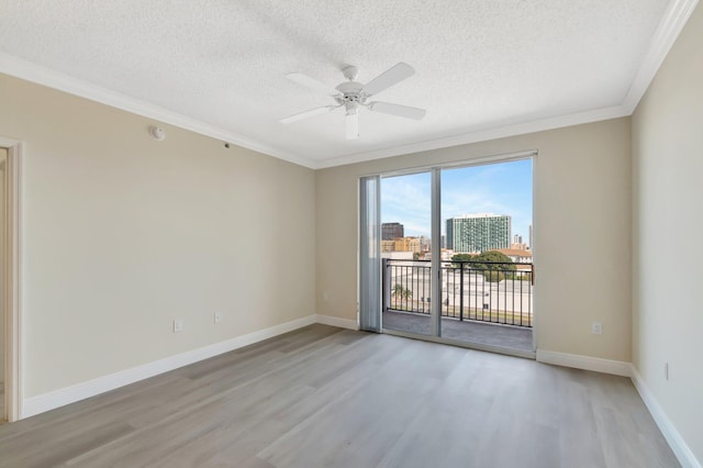 empty room with light wood-style floors, crown molding, a textured ceiling, and baseboards