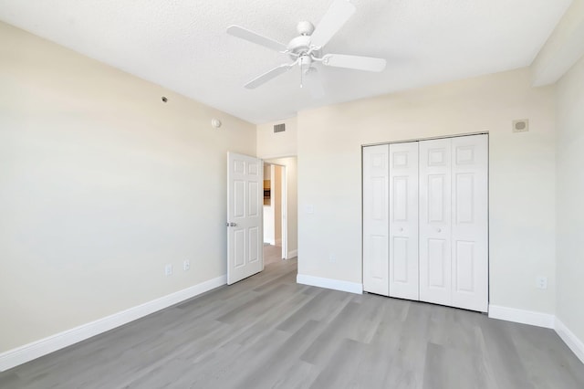 unfurnished bedroom featuring a textured ceiling, wood finished floors, visible vents, and baseboards