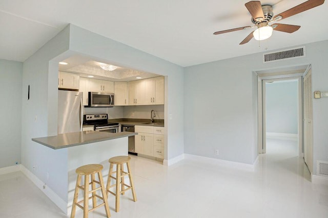 kitchen with visible vents, white cabinets, stainless steel appliances, a kitchen bar, and a sink