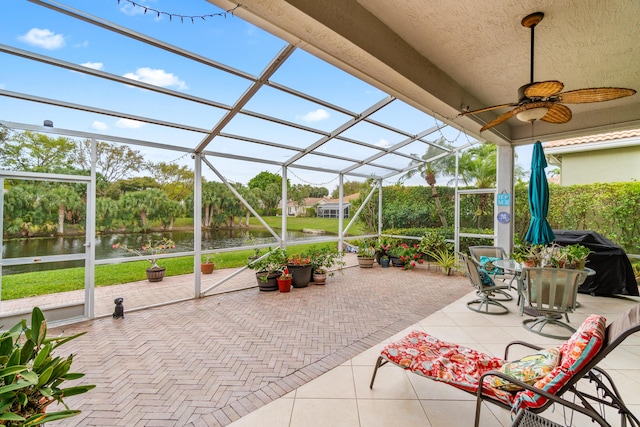 view of patio / terrace featuring a lanai, a water view, ceiling fan, and area for grilling