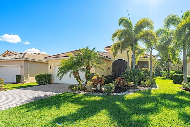 view of front of house featuring decorative driveway, stucco siding, an attached garage, a tiled roof, and a front lawn