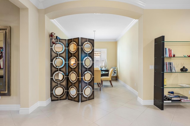 interior space with arched walkways, tile patterned flooring, crown molding, and baseboards