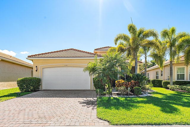 view of front of home featuring a garage, stucco siding, a tiled roof, decorative driveway, and a front yard