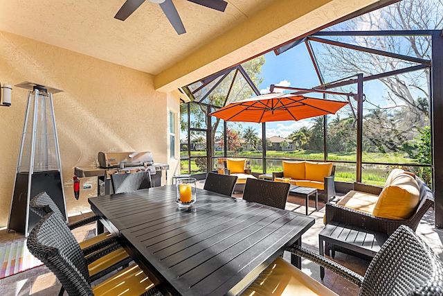 view of patio featuring outdoor dining space, glass enclosure, ceiling fan, and an outdoor hangout area