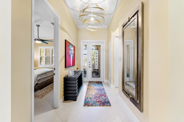 tiled entrance foyer with a notable chandelier, baseboards, and crown molding