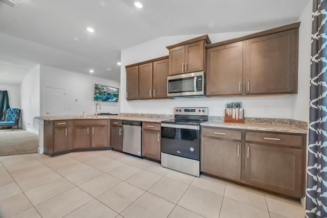 5361 San Benedetto Pl, Fort Pierce, FL 34951 - kitchen with stainless steel appliances, light tile patterned flooring, vaulted ceiling, a sink, and a peninsula