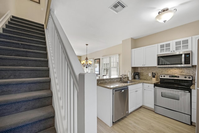 kitchen featuring a sink, visible vents, white cabinets, appliances with stainless steel finishes, and tasteful backsplash