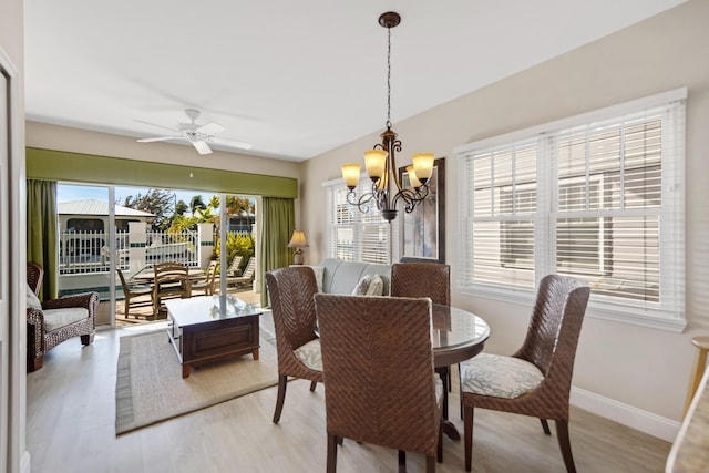 dining room with baseboards, light wood finished floors, and ceiling fan with notable chandelier