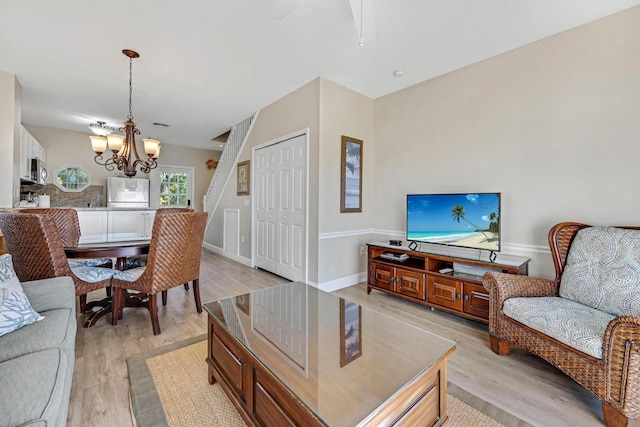 living area featuring a chandelier, light wood finished floors, and baseboards