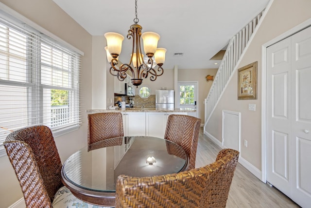 dining area featuring light wood finished floors, visible vents, baseboards, stairway, and a chandelier