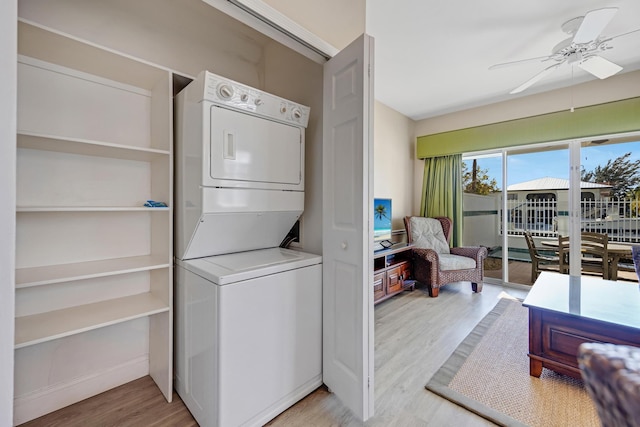 clothes washing area featuring stacked washer and dryer, ceiling fan, laundry area, and wood finished floors