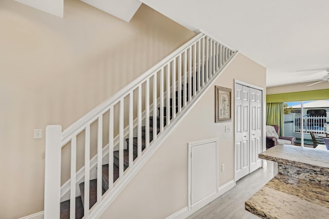 stairway with a ceiling fan, baseboards, and wood finished floors