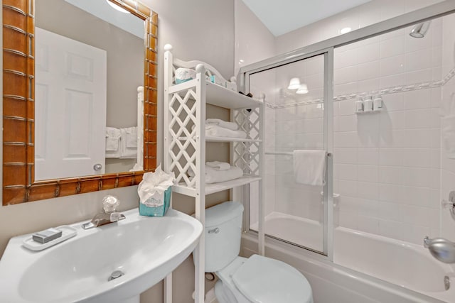 full bath featuring shower / bath combination with glass door, a sink, and toilet