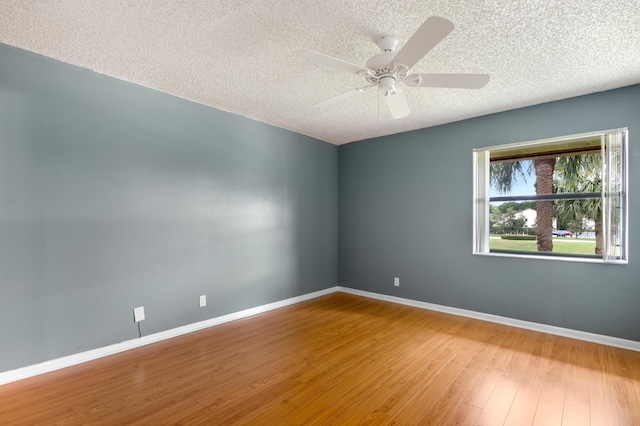 spare room featuring a textured ceiling, baseboards, and wood finished floors