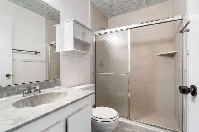 bathroom with toilet, a stall shower, and vanity