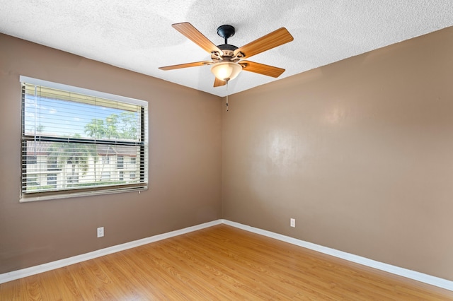 spare room featuring light wood-style floors, a textured ceiling, baseboards, and a ceiling fan