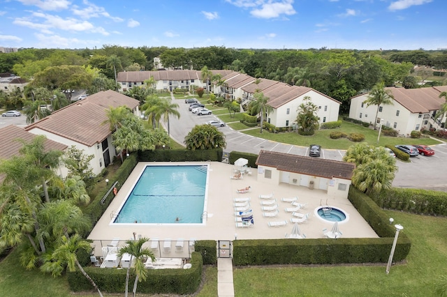 community pool with a patio area, fence, and a residential view