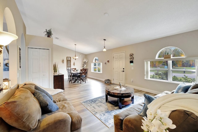 living area featuring vaulted ceiling, light wood-type flooring, and baseboards