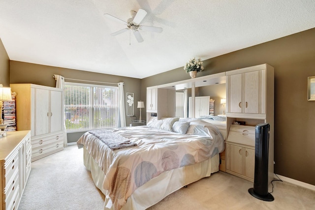 bedroom featuring light colored carpet, a ceiling fan, vaulted ceiling, a textured ceiling, and baseboards