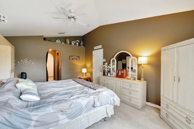 bedroom with lofted ceiling, visible vents, light carpet, and arched walkways