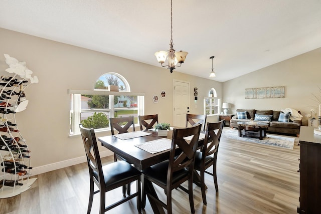 dining space with lofted ceiling, baseboards, a notable chandelier, and light wood-style floors