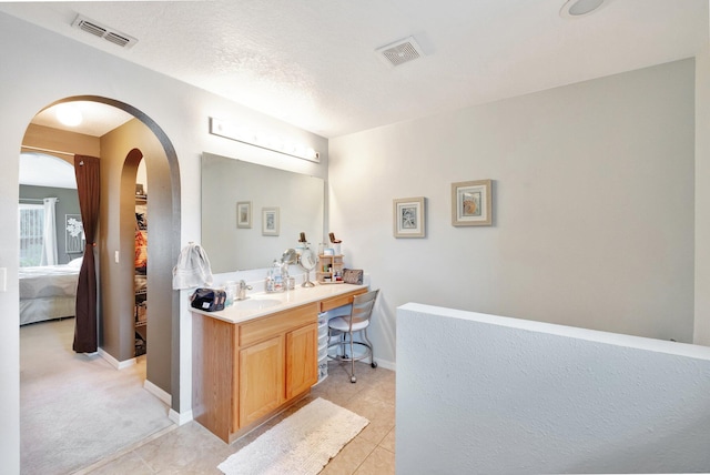 office space featuring arched walkways, visible vents, a sink, and light tile patterned floors