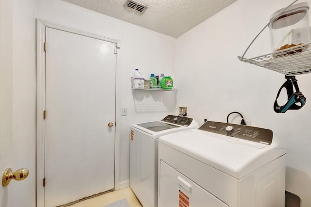 washroom with light tile patterned floors, visible vents, a textured ceiling, laundry area, and independent washer and dryer