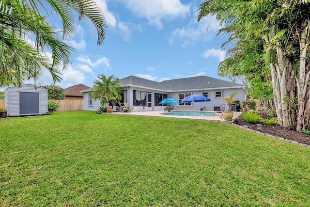 back of house featuring an outbuilding, fence, a sunroom, an outdoor pool, and a storage unit