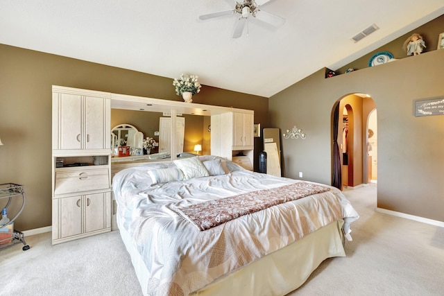 bedroom with lofted ceiling, light colored carpet, visible vents, and arched walkways