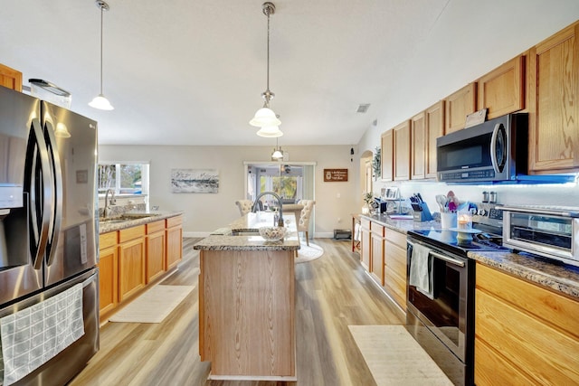 kitchen with stainless steel appliances, a sink, a center island with sink, and light wood-style floors