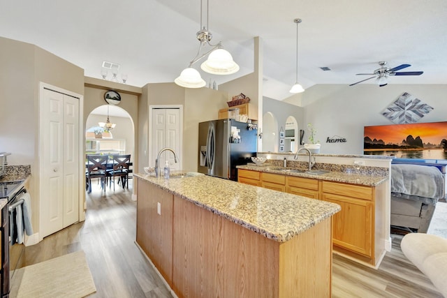 kitchen with arched walkways, stainless steel refrigerator with ice dispenser, a sink, and open floor plan