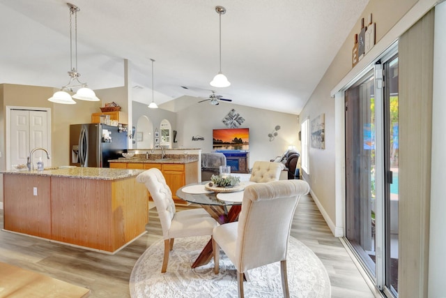 dining space with lofted ceiling, ceiling fan, light wood-type flooring, and baseboards