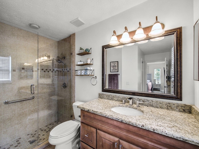 bathroom with toilet, a stall shower, visible vents, and vanity