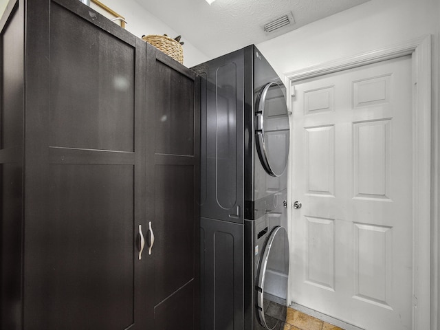 interior space featuring cabinet space, a textured ceiling, visible vents, and stacked washer / dryer