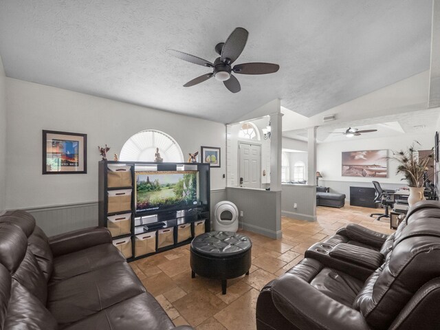 living room featuring lofted ceiling, a wealth of natural light, decorative columns, and stone tile floors