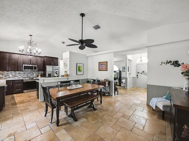 dining area featuring lofted ceiling, stone tile flooring, visible vents, a textured ceiling, and ceiling fan with notable chandelier