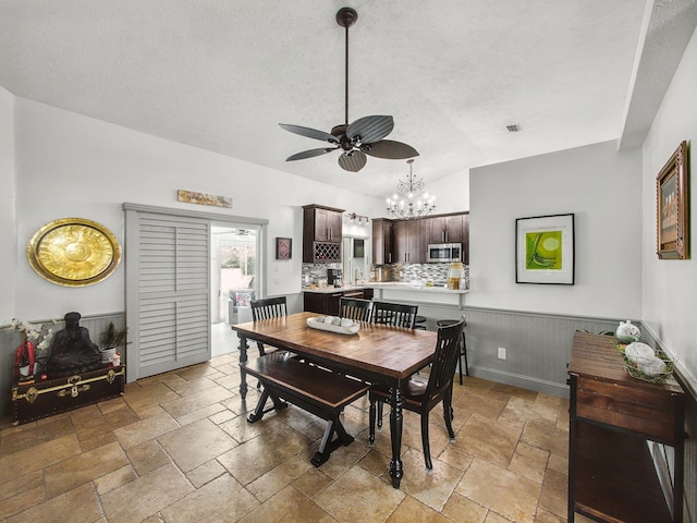 dining space with lofted ceiling, a textured ceiling, and stone tile flooring