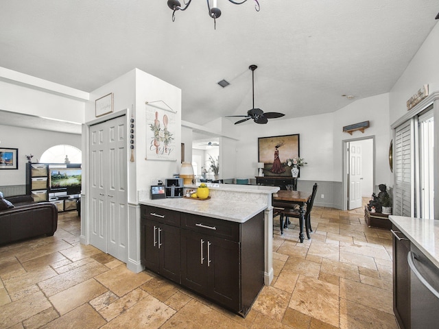 kitchen with stone tile floors, open floor plan, ceiling fan, light stone countertops, and a peninsula