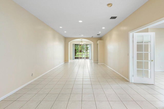 unfurnished room featuring light tile patterned floors, visible vents, arched walkways, and baseboards