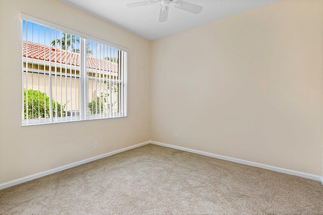 spare room featuring carpet flooring, baseboards, and ceiling fan