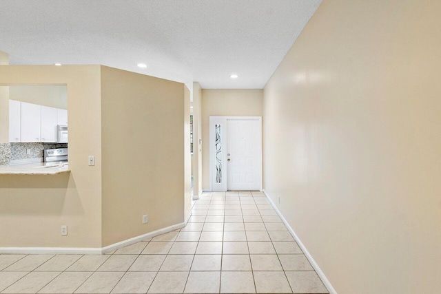 interior space featuring light tile patterned floors, recessed lighting, a textured ceiling, and baseboards