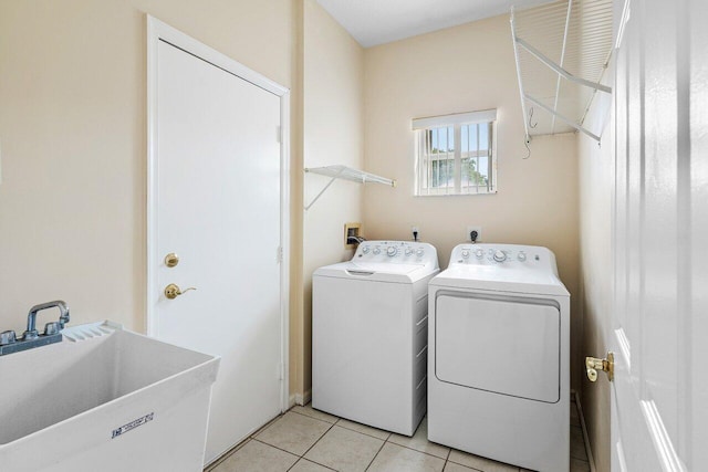 clothes washing area with laundry area, light tile patterned flooring, separate washer and dryer, and a sink