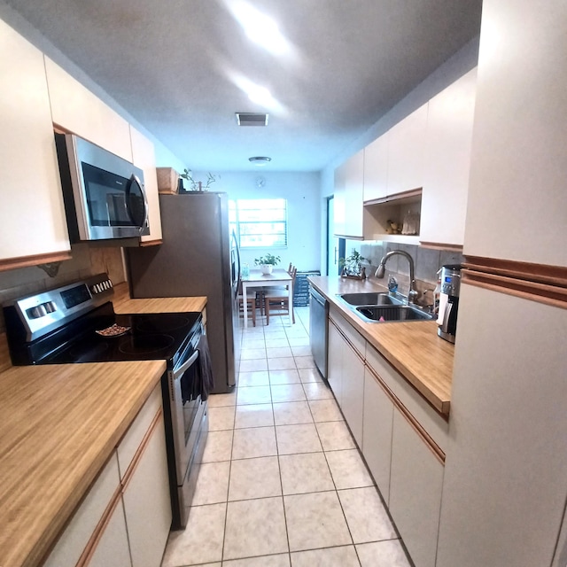 5070 Nesting Way Unit B, Delray Beach, FL 33484 - kitchen with light countertops, appliances with stainless steel finishes, light tile patterned flooring, white cabinetry, and a sink