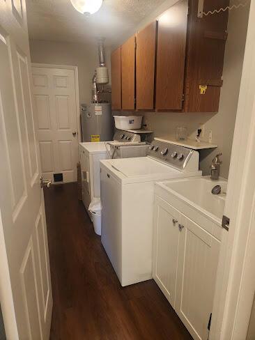 clothes washing area featuring cabinet space, water heater, dark wood-style floors, and washer and dryer