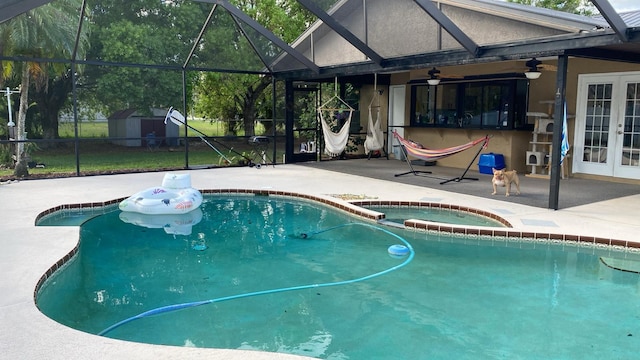 view of swimming pool with an outbuilding, french doors, a storage shed, a patio area, and ceiling fan